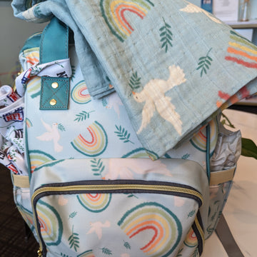 A Catholic diaper bag and swaddle featuring doves, rainbows, and olive branches from Noah's Ark