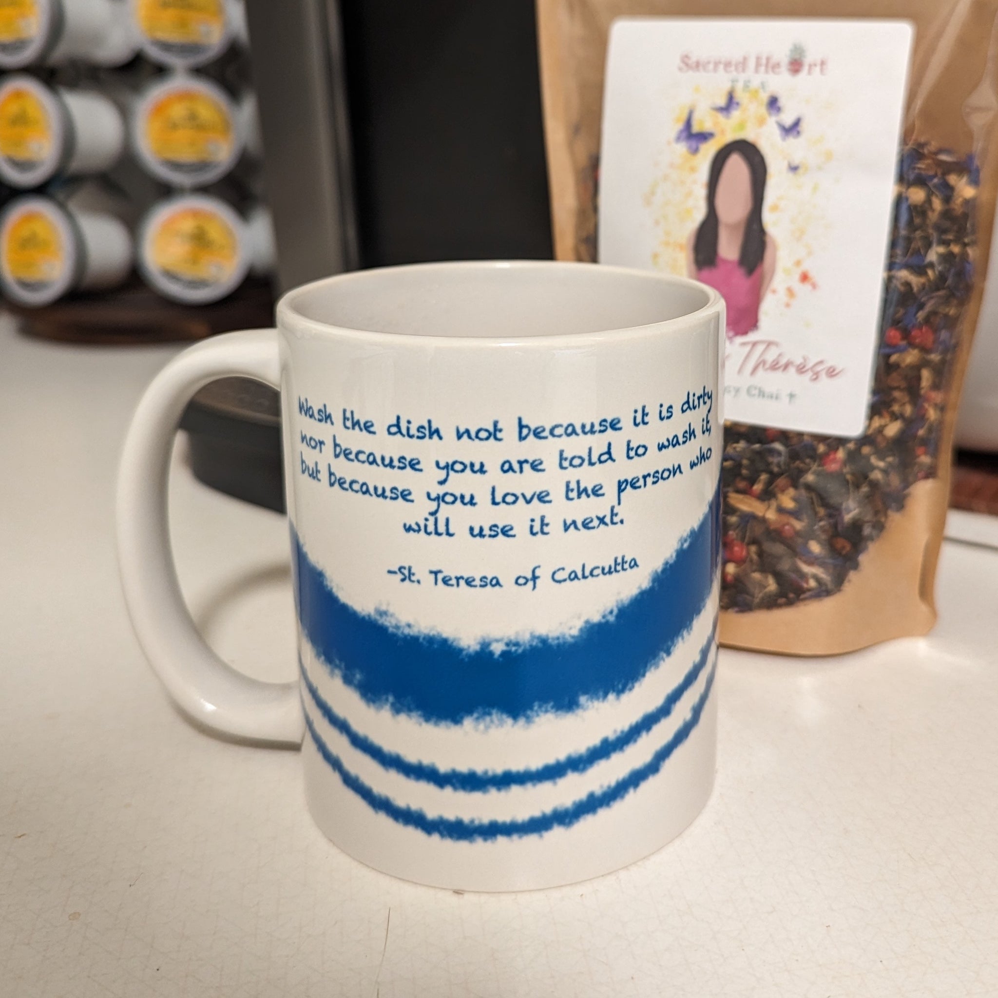 A Catholic mug featuring Mother Teresa's quote Wash the Dish with blue stripes