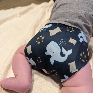 A baby wearing a Catholic cloth diaper featuring the Jonah's Wait design