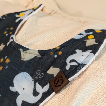 Catholic baby bib featuring Jonah's Wait design with whales, scrolls, and three suns and moons