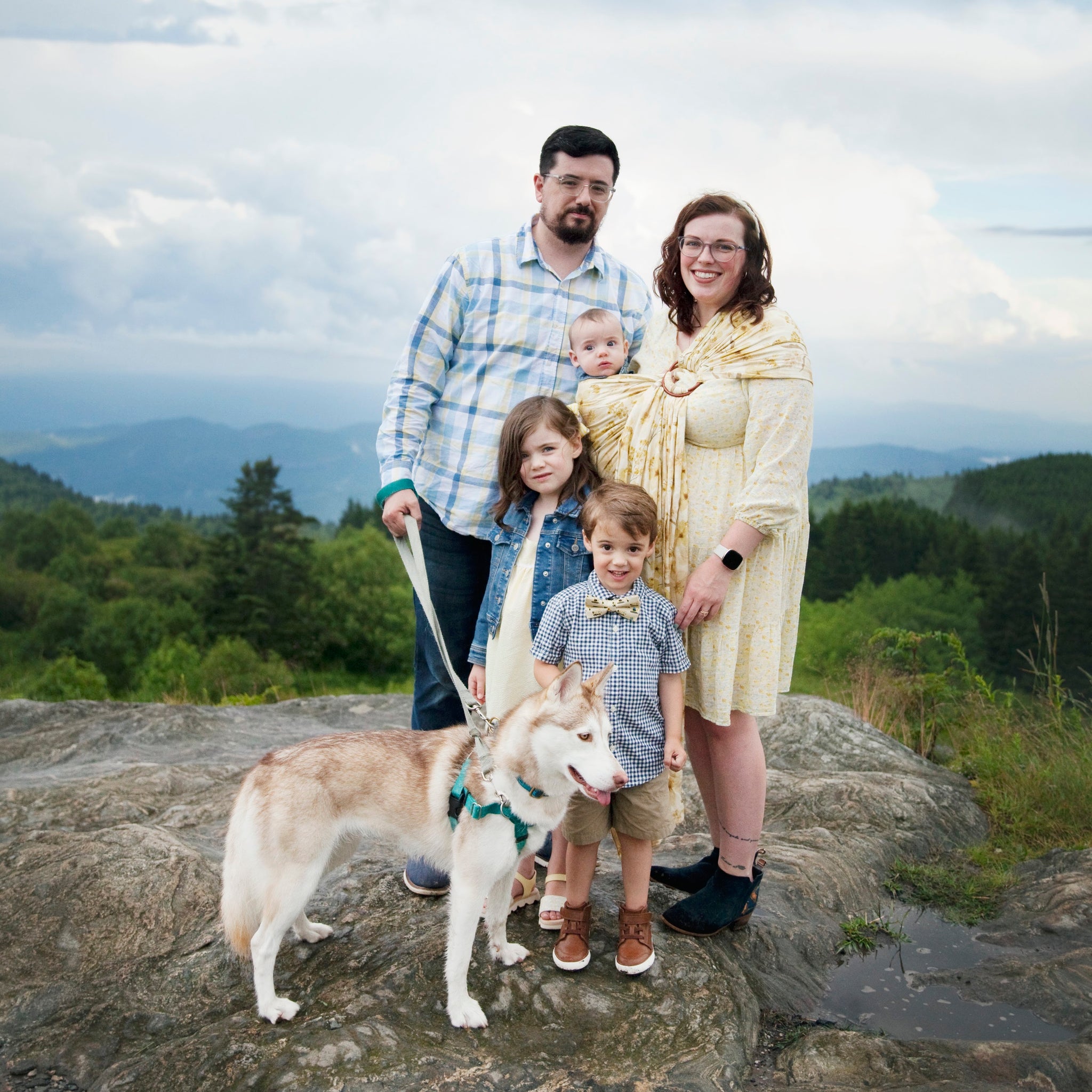 A man, woman, two children, and a baby standing on a mountaintop with their dog. The woman is Ivy Doe & Co owner Riley with her family.