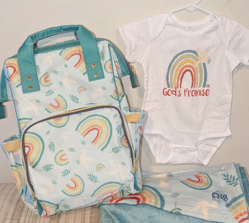 A Catholic diaper bag, onesie and blanket all with a rainbow, dove and olive leaf design. The onesie also features the phrase "God's Promise".