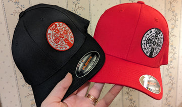 One men's or women's black Catholic hat with a red and silver St. Benedict medal on the front. One red hat with a silver and black St. Benedict medal on the front.